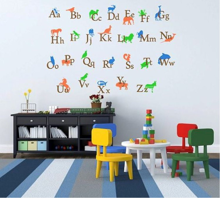 Decoração estimulante de alfabeto na parede, conciliando mesa de estudo e brincar com estante para guardar os livros. Perceba o toque das cores claras, para dar mais tranquilidade ao ambiente